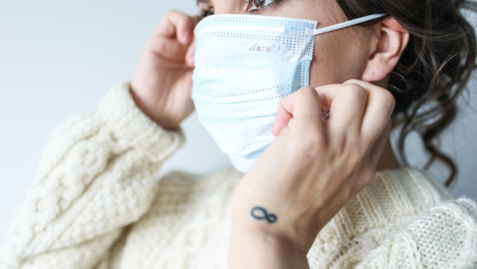 Muller colocando unha máscara quirúrxica antes de sair da casa | Foto Pixabay