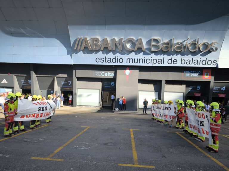 Abel Caballero recibido por un corredor de bombeiros con pancartas de protesta en Balaídos